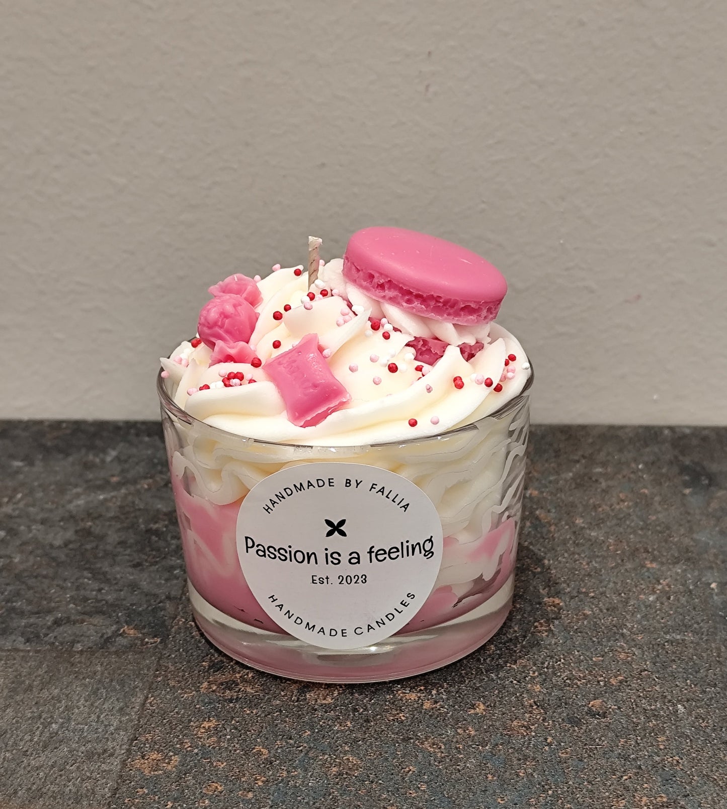 Candle in a glass jar with pink and white design on a gray surface