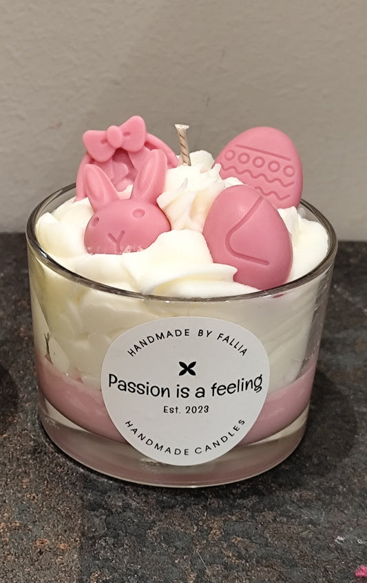 Candle with pink bunny figures and whipped cream in a glass container, featuring a 'Passion is a feeling' label.
