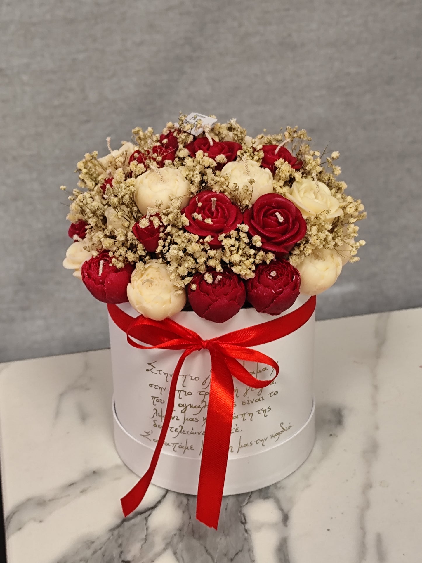 red and white candle flowers and a red ribbon on a wooden surface.