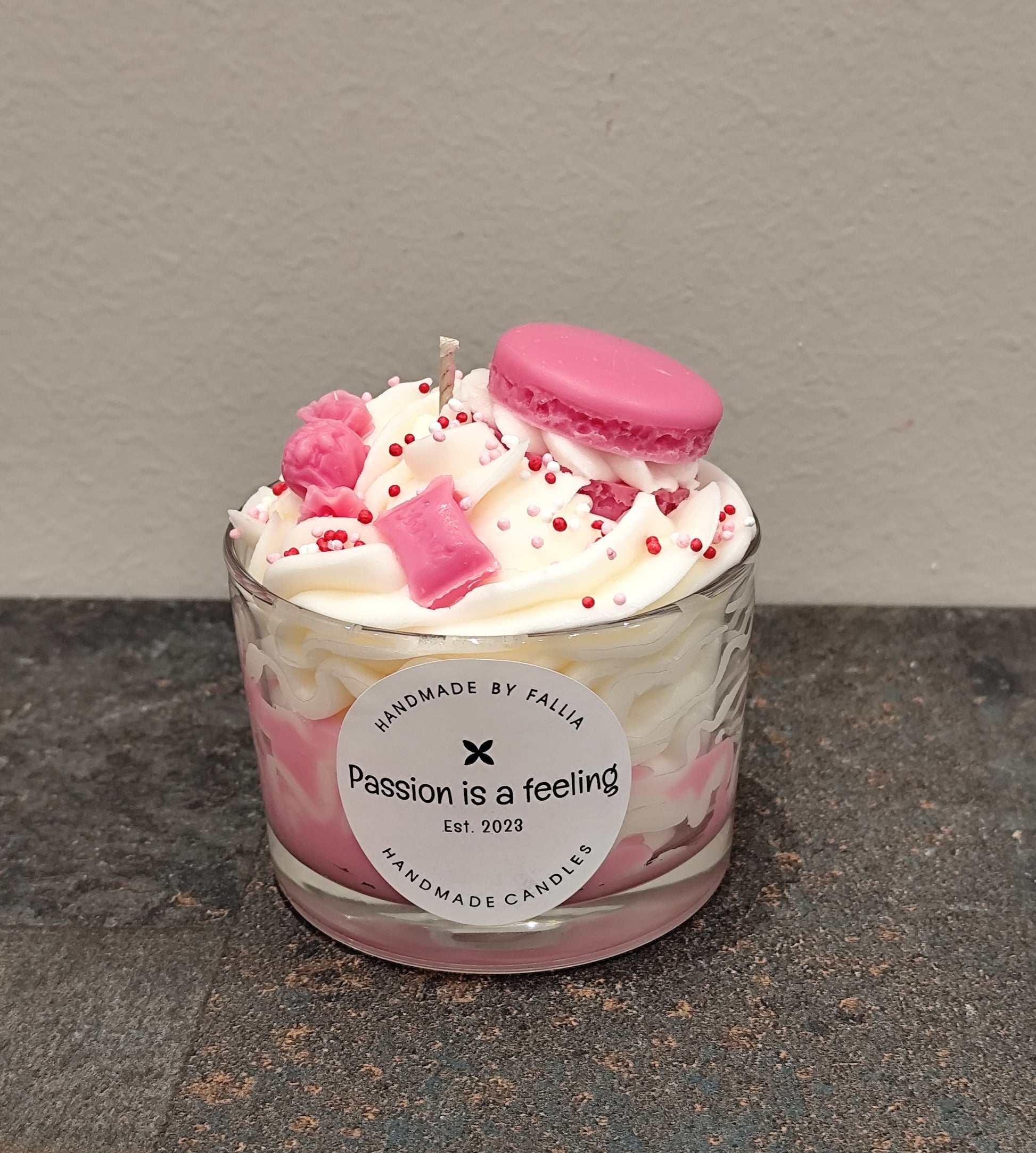 Candle in a glass jar with pink and white design on a gray surface