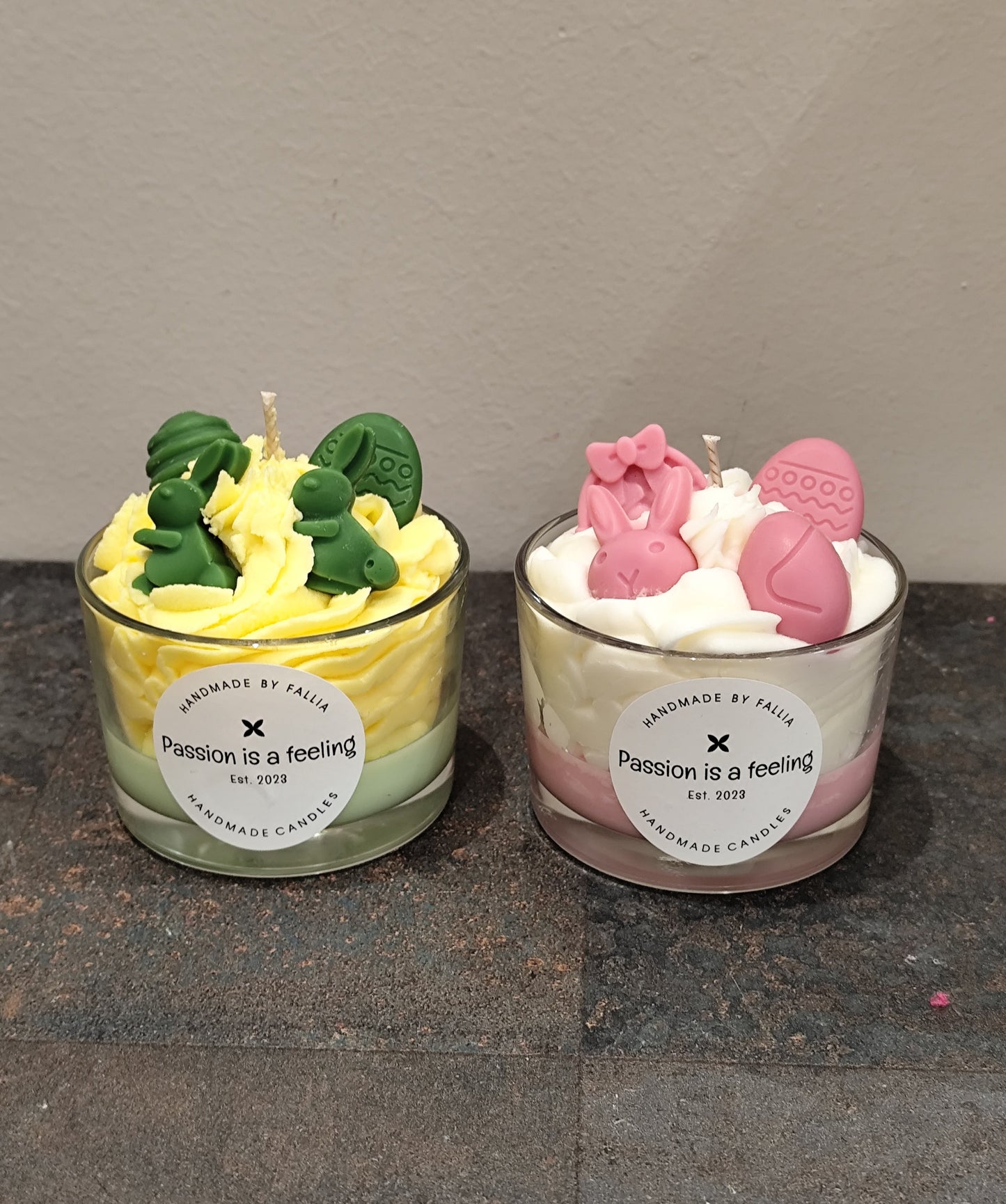 Two small candles in glass jars with decorative elements on a dark surface.