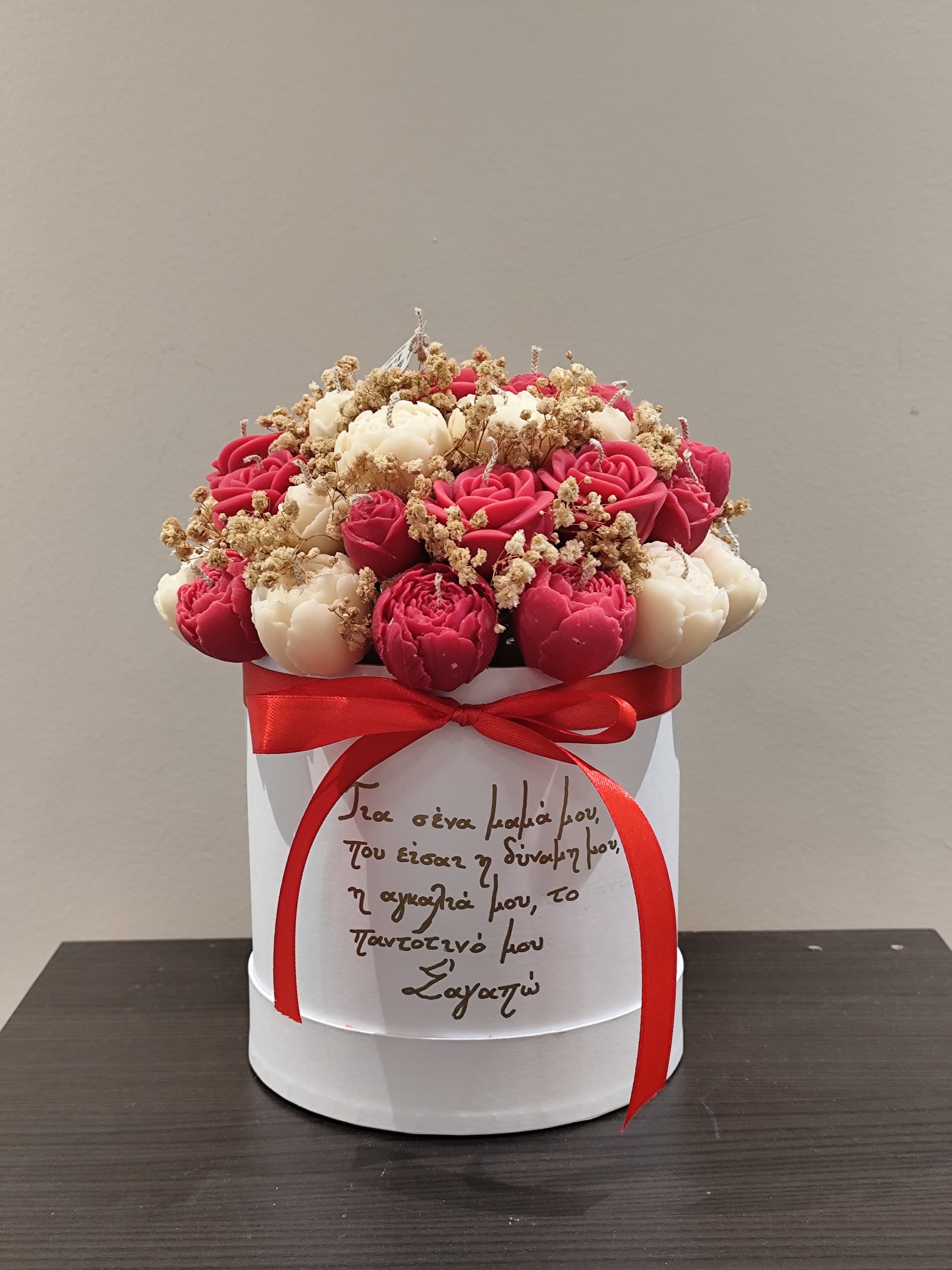  red and white candle flowers and a red ribbon on a wooden surface.
