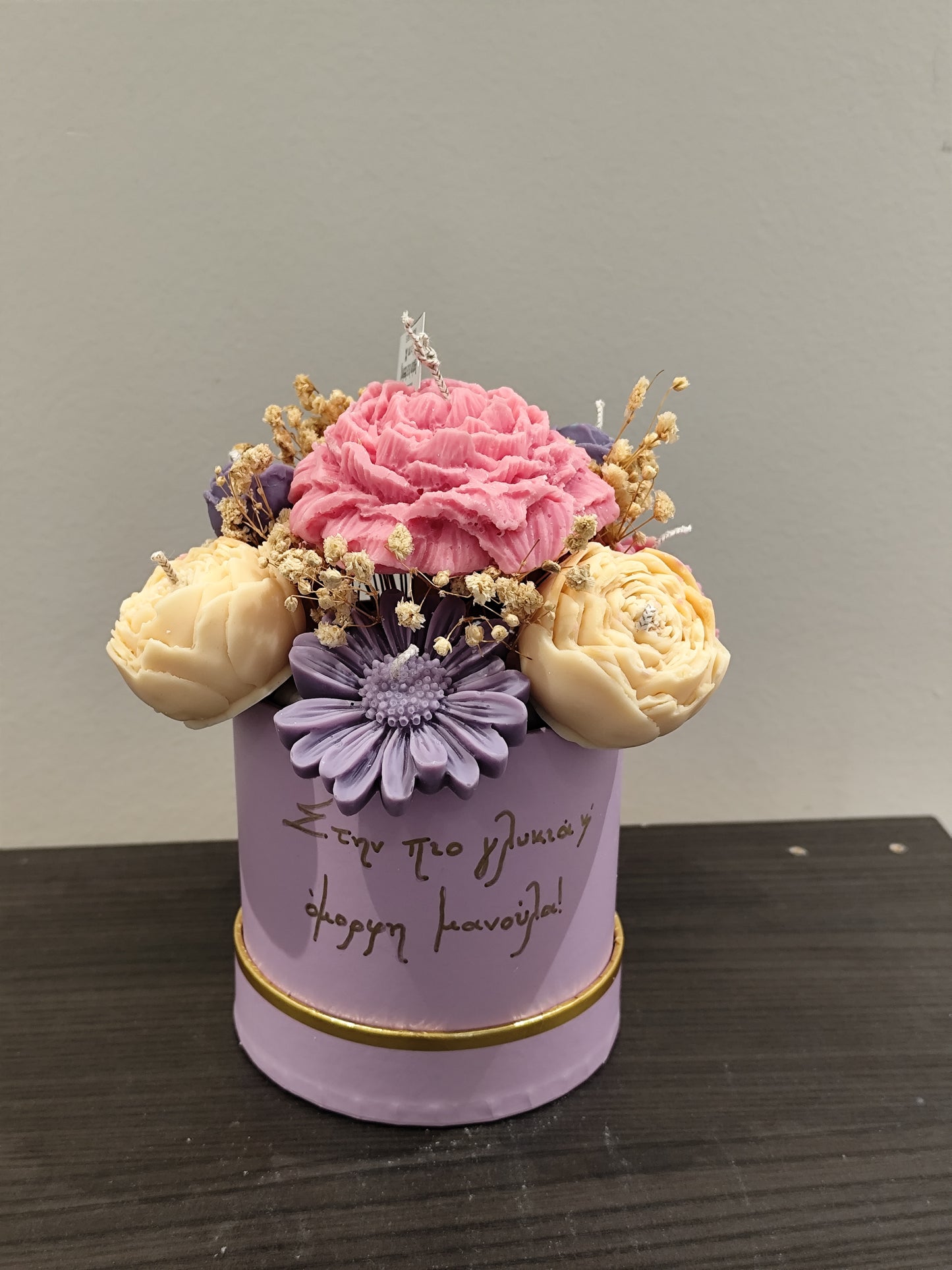 Candle flower arrangement in a purple container with text on a gray background