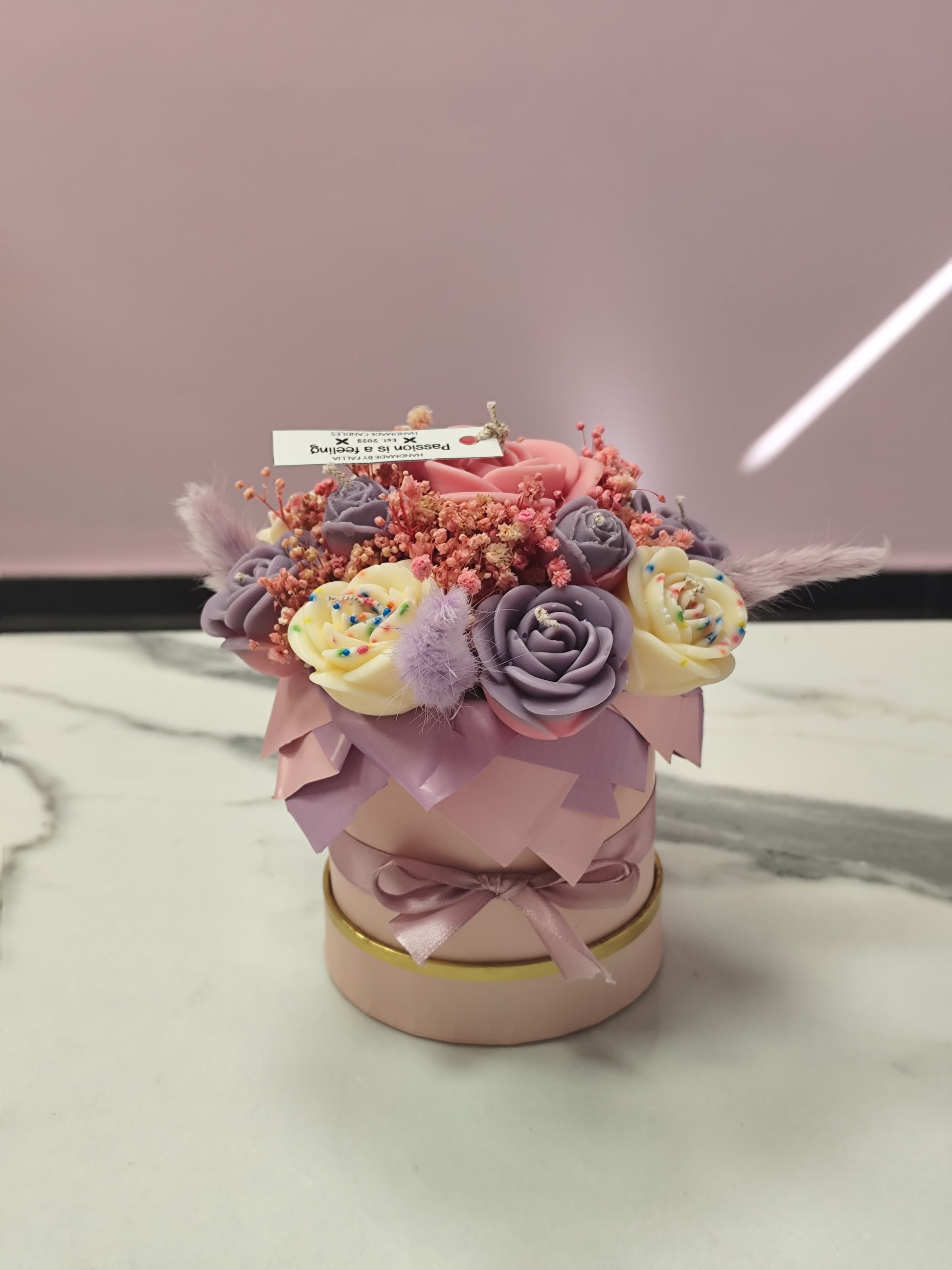 Decorative candle flower  a pink container on a marble surface with a blurred background