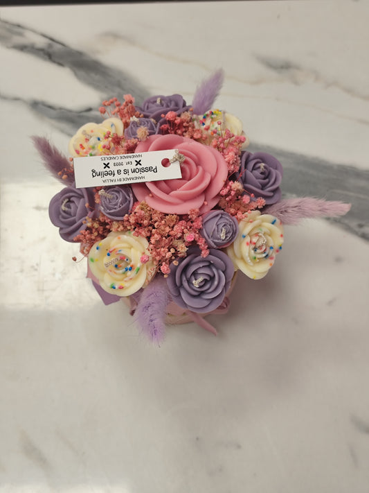 Decorative candle flower  with pink and purple flowers on a marble surface