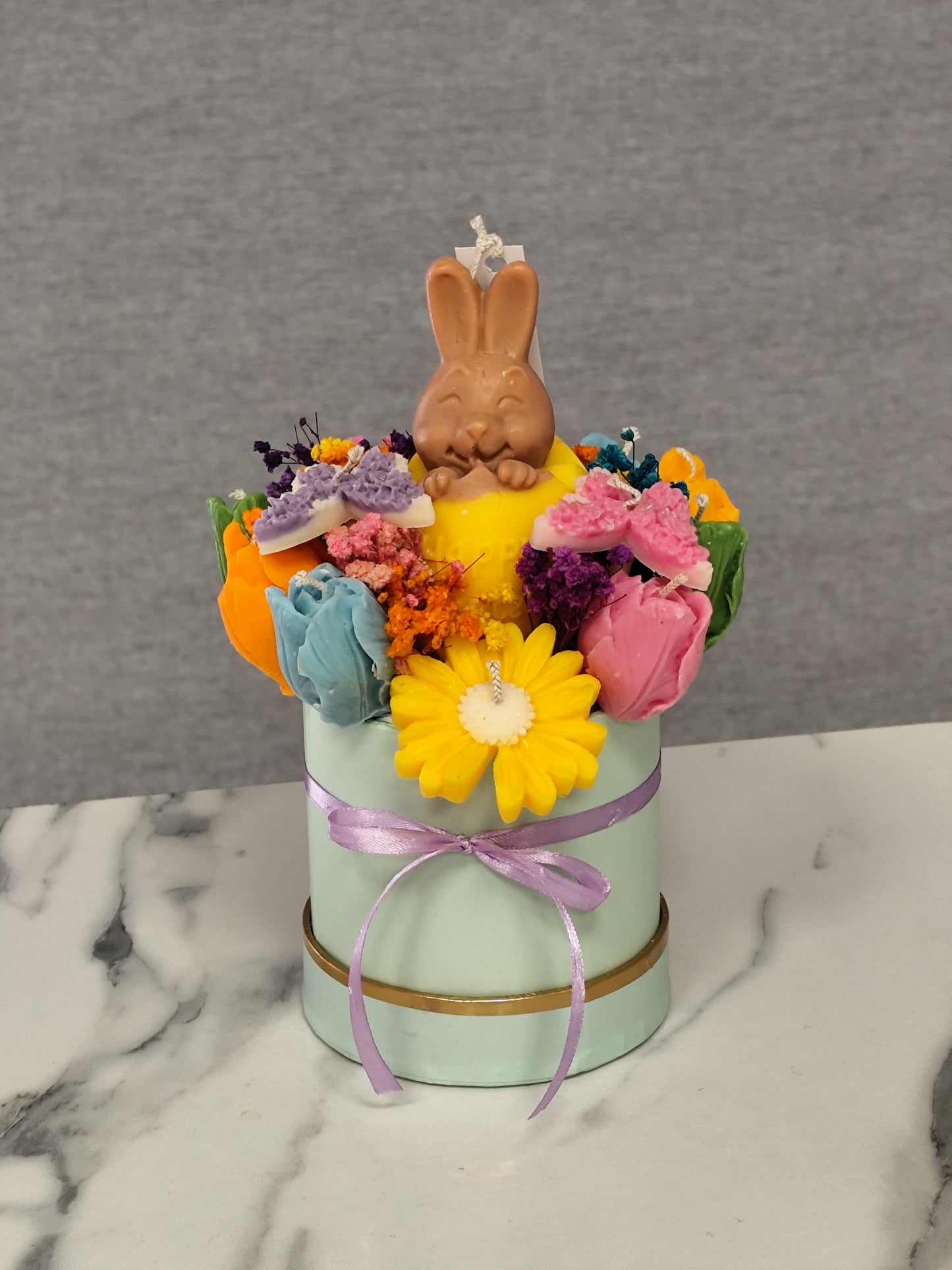 colorful candle flowers and a bunny figure on a marble surface.