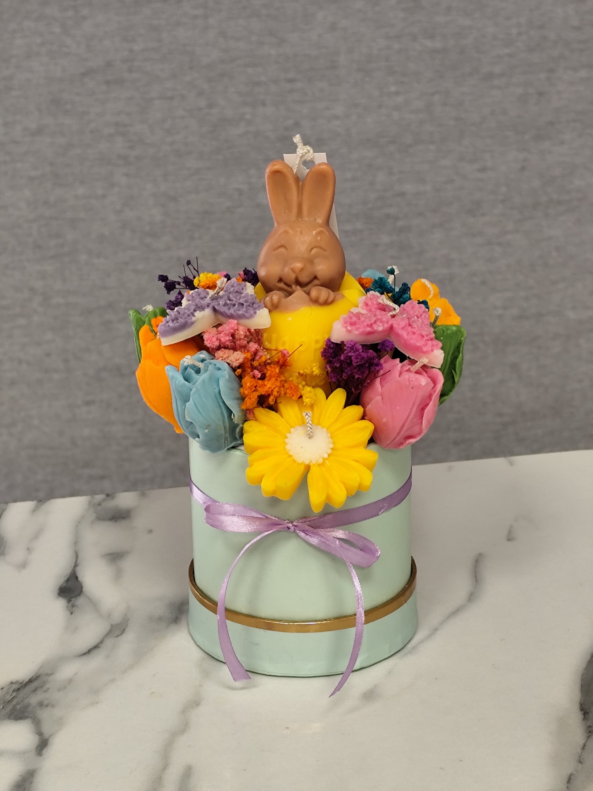 colorful candle flowers and a bunny figure on a marble surface.
