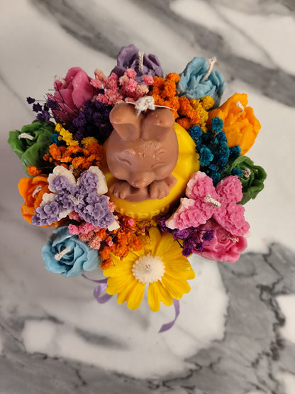 colorful candle flowers and a bunny figure on a marble surface.