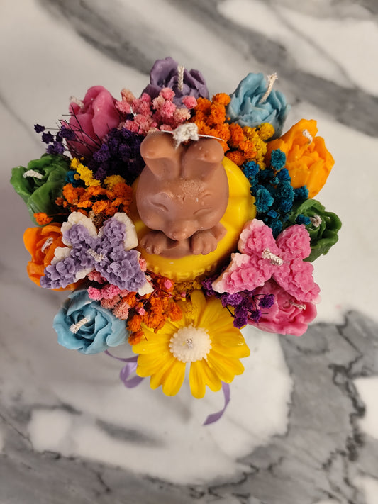 colorful candle flowers and a bunny figure on a marble surface.