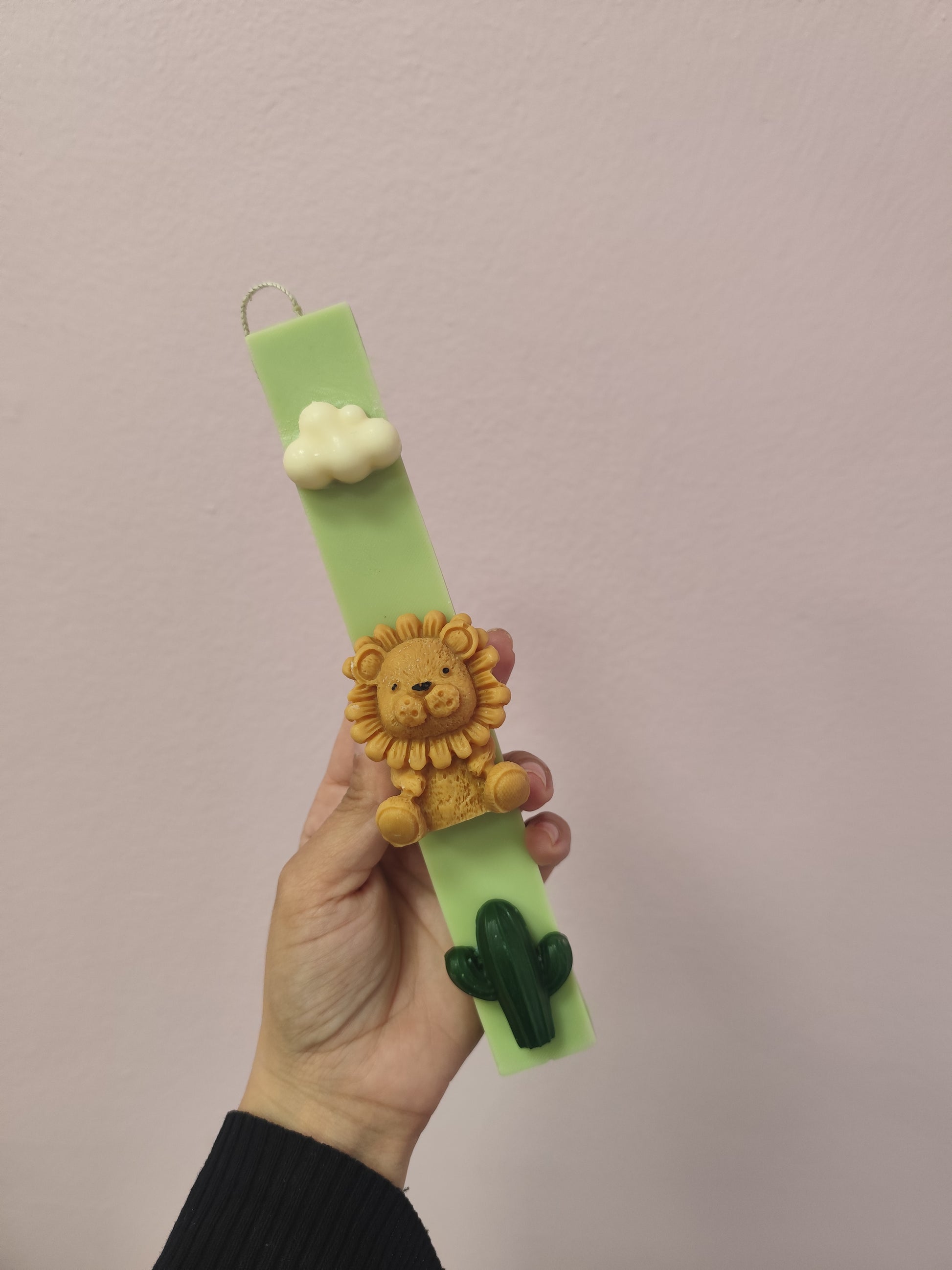 Candle with a lion charm against a plain background