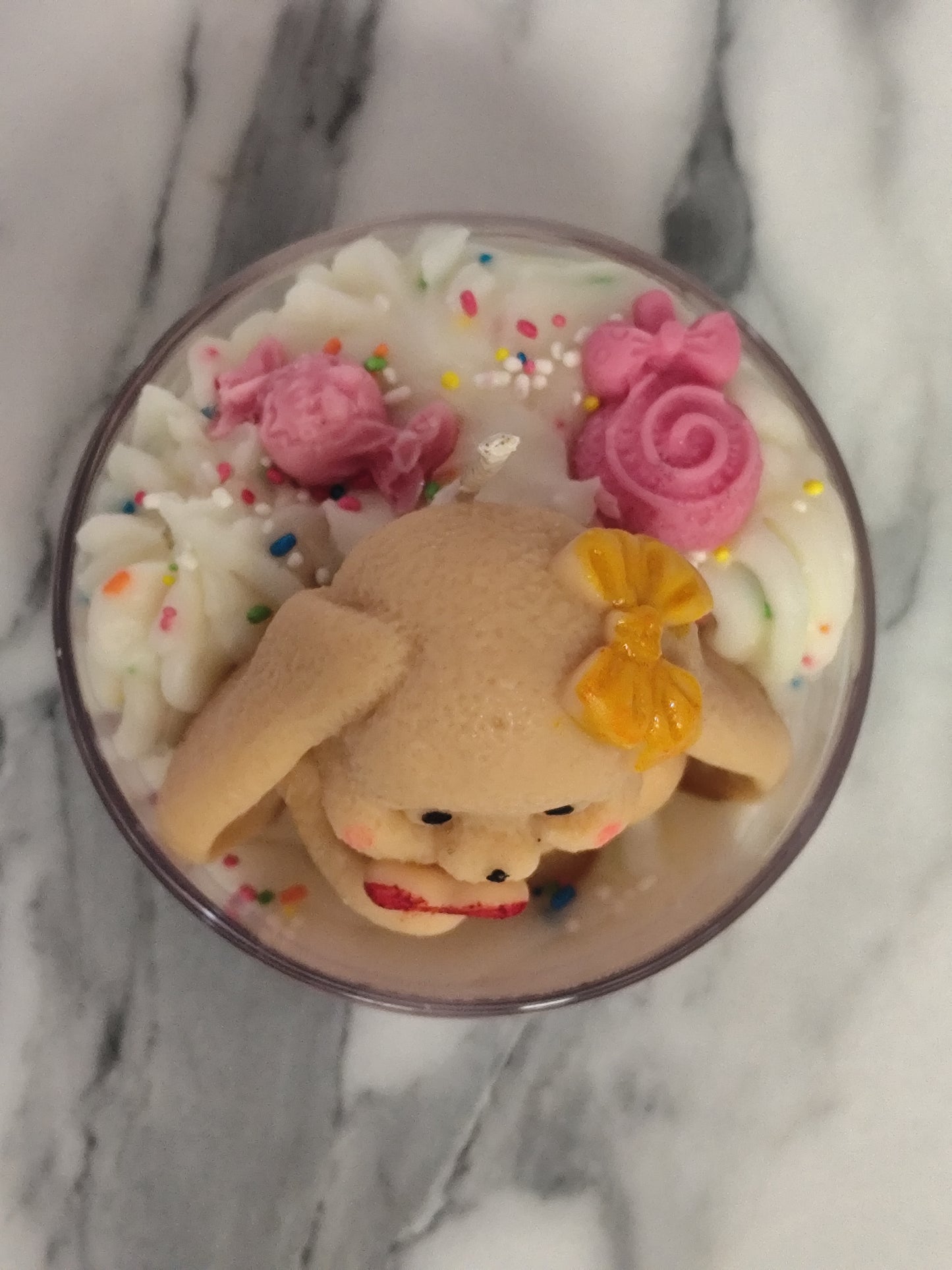 Candle with a bear decoration on a marble surface