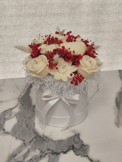 Decorative flower arrangement in a white box with red flowers on a marble surface