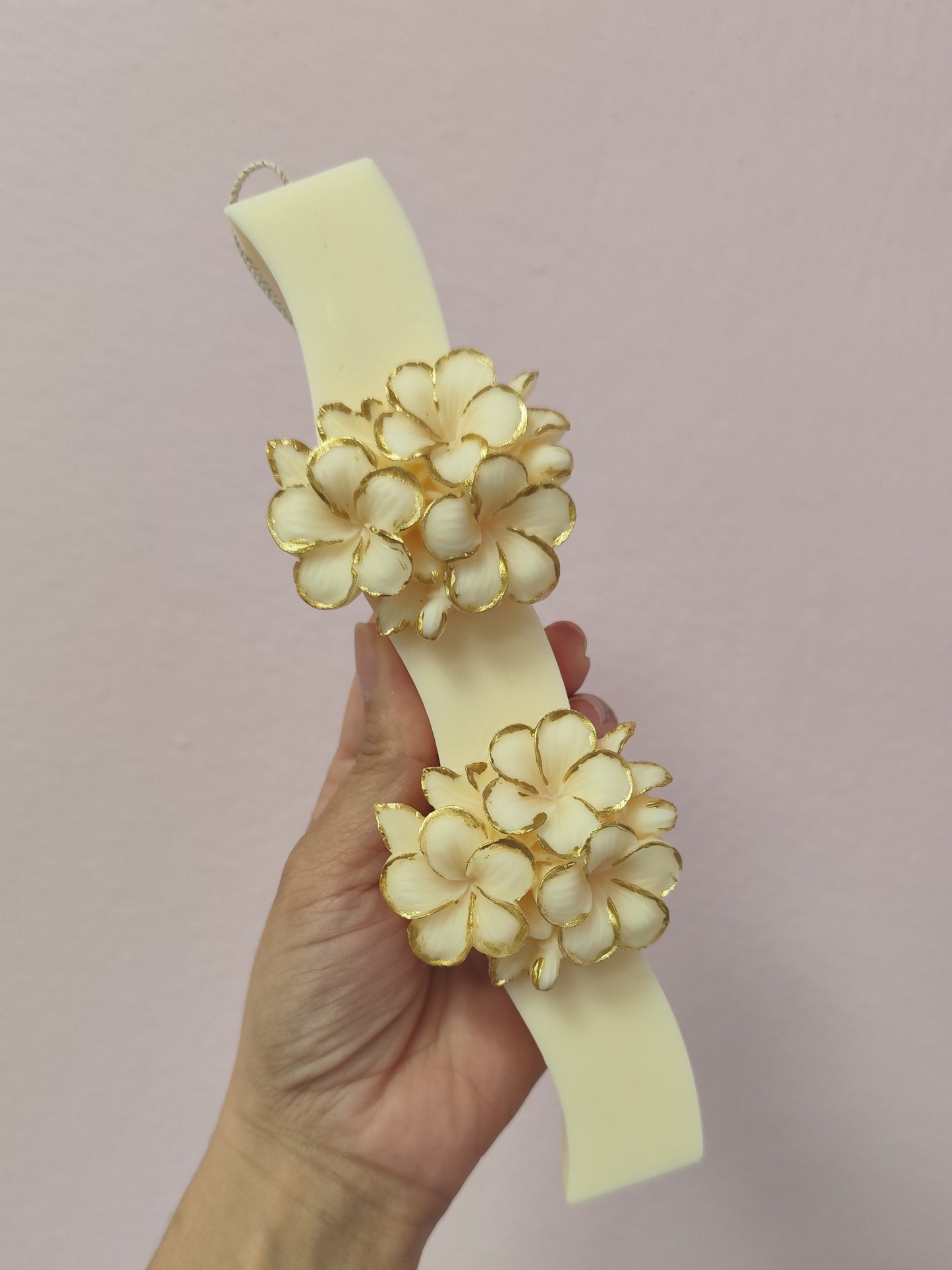  floral designs  easter candle by a hand against a pink background