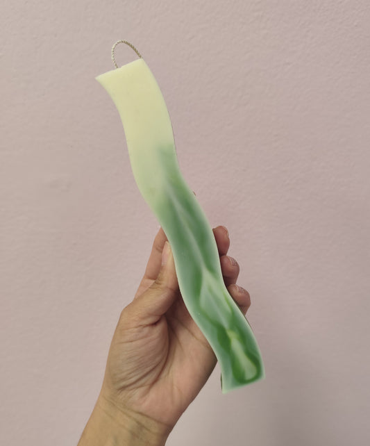 Hand holding a green and white striped object against a plain background