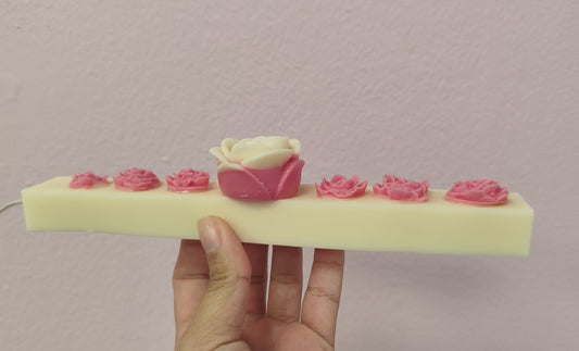 Hand holding a rectangular block with floral designs on a plain background